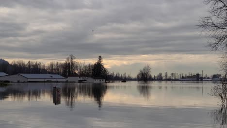 Rescue-Helicopter-in-the-Distance-Flying-Over-Flooded-Homes-and-Farmland,-Abbotsford,-British-Columbia,-Canada-slider-shot