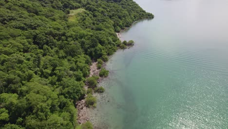 Aerial-Dolly-In-Türkisfarbenem-Meer-Und-Dichter-Grüner-Regenwaldküste-In-Nacascolo-Beach-An-Einem-Bewölkten-Tag,-Papagayo-Halbinsel,-Costa-Rica