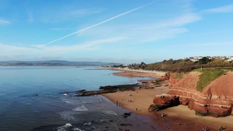 Aerial-Of-Orcombe-Beach-And-Cliff-Coastline-In-Exmouth-With-Visitors-On-Beach-On-Sunny-Day