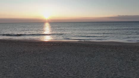 Ein-Faszinierender-Sonnenuntergang-Am-Strand:-über-Einen-Strand-Fliegen-Und-Der-Sonne-Folgen,-Die-Sich-Auf-Der-Wasseroberfläche-Spiegelt