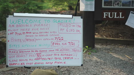Static-view-of-directives-written-for-the-tourists-on-a-white-board-related-to-booking-of-camp-sites-in-Glacier-NP-Campground-and-Creek,-United-States