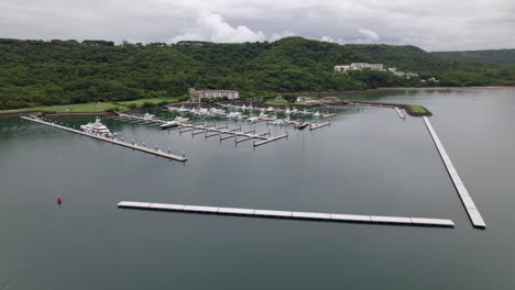 Aerial-truck-right-of-docks-in-sea-shore-and-woods-near-Planet-Hollywood-hotel-in-Nacascolo-beach-in-Papagayo-Peninsula,-Costa-Rica
