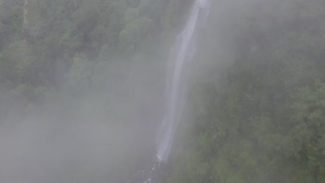 Aerial-dolly-in-of-clouds-revealing-Las-Lajas-misty-waterfall-surrounded-by-green-dense-rainforest,-San-Luis-Morete,-Costa-Rica