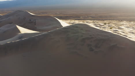 Aerial-drone-view-of-spectacular-majestic-sand-piles-of-Kelso-Dunes-at-sunrise,-California