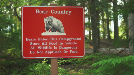 A-Bear-Country-warning-sign-near-a-road-inside-Glacier-National-Park,-Montana,-U