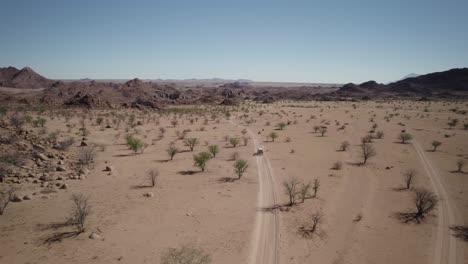 Car-on-sandy-road-in-rugged-Namibian-landscape,-wild-African-experience