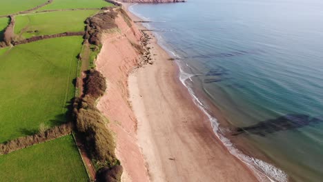 Aerial-Along-Exmouth-Coastline-And-Beach-With-Tilt-Up-Reveal-Towards-Horizon