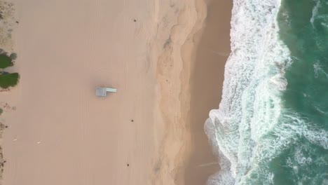 Foamy-Waves-Splashing-On-Sandy-Beach---aerial-top-down