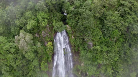 Aerial-pan-left-of-Las-Lajas-waterfall-streaming-down-a-high-cliff-surrounded-by-dense-green-rainforest,-San-Luis-Morete,-Costa-Rica