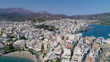 Drone-shot-over-the-marina,-seaside-boulevard,-beaches,-summer-in-Agios-Nikolaos-Crete-Greece