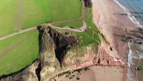Aerial-Over-Orcombe-Point-Cliff-Coastline-In-Exmouth-With-Visitors-On-Beach-On-Sunny-Day