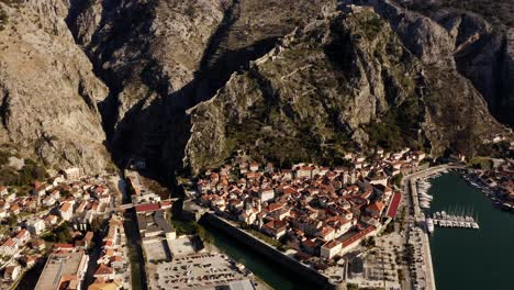 AERIAL---Bay-of-Kotor,-mountains,-and-ancient-city-of-Kotor,-Montenegro,-rising
