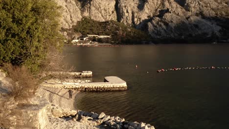 AERIAL---Sunbathed-Bay-of-Kotor-in-the-city-of-Kotor,-Montenegro,-reverse-shot