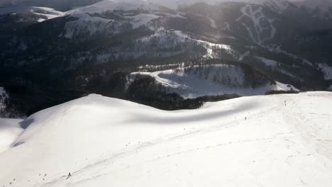AERIAL---People-skiing-in-the-mountains-at-Kolasin-ski-resort,-Montenegro,-pan-right