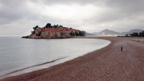 AERIAL---Sveti-Stefan-island-resort-and-beach-on-the-Adriatic-Sea,-Montenegro,-forward