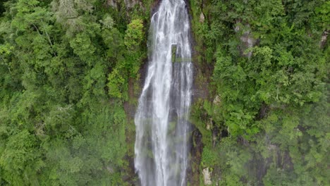 Aerial-pan-right-of-Las-Lajas-misty-waterfall-streaming-down-high-cliff-covered-in-dense-green-forest,-San-Luis-Morete,-Costa-Rica
