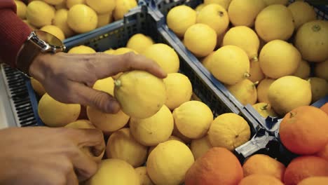 Close-up-of-a-worker's-hands-placing-fresh-lemons-on-display-at-a-grocery-store