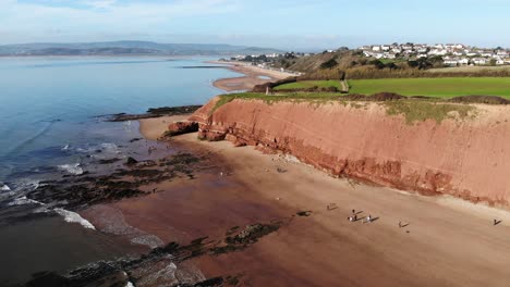 Aerial-Of-Orcombe-Cliffs-Coastline-In-Exmouth-With-Visitors-On-Beach-On-Sunny-Day