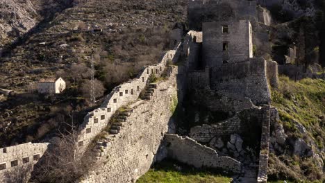 AERIAL---Ancient-city-walls,-Kotor,-Montenegro,-a-UNESCO-World-Heritage-Site,-reverse