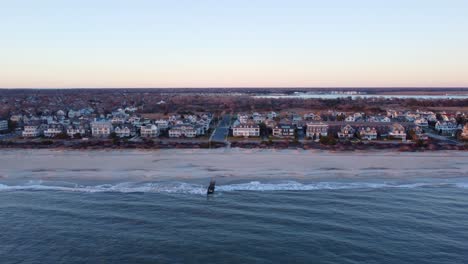 Aerial-drone-shot,-flying-along-the-beach-during-the-golden-hour-in-Cape-May-New-Jersey,-Cape-May-County