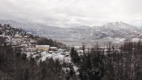 AERIAL---Snowy-village-of-Virpazar-and-its-mountains-in-Bar,-Montenegro,-forward