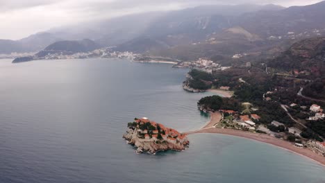 AERIAL---Sveti-Stefan-island,-tombolo,-and-Villa-Milocer-in-Montenegro,-reverse