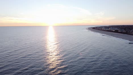 A-beautiful-aerial-drone-shot,-flying-towards-the-sun-during-the-golden-hour-in-Cape-May-New-Jersey,-Cape-May-County