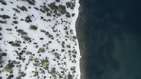 Topdown-aerial-of-the-shoreline-of-Emerald-Bay-with-heavy-snowfall-on-the-slope