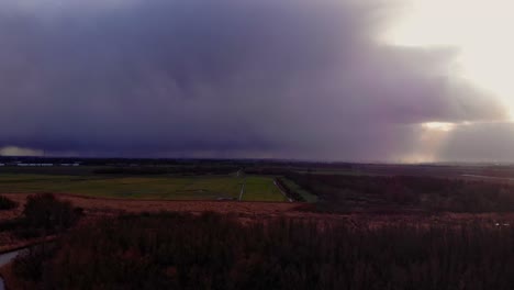 Aerial-View-Across-Nature-Landscape-Under-Dark-Overcast-Clouds-With-Dolly-Left-Reveal-Of-Sun-Shine-Beams-Through-Clouds-In-Zwijndrecht