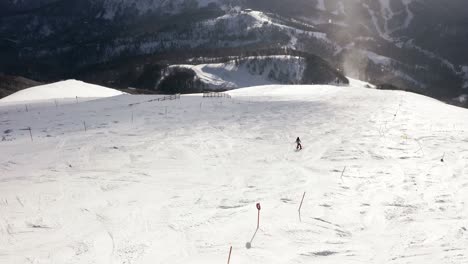 AERIAL---Person-skiing-in-mountains-at-Kolasin-ski-resort,-Montenegro,-tracking-shot
