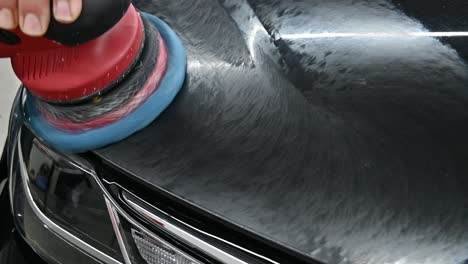 Hands-of-repair-man-polishing-modern-black-vehicle-with-industrial-tool,-close-up-view