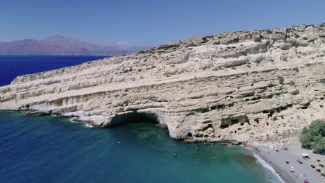 Hermosa-Vista-Desde-Un-Dron-Volando-Sobre-La-Playa-Y-La-Bahía-En-Matala-Creta-Grecia