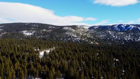 A-beautiful-aerial-drone-shot,-flying-over-the-woods-towards-the-mountains-in-Lake-Tahoe,-Nevada-California