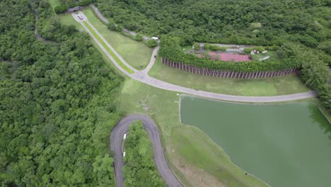 Aerial-dolly-out-of-curvy-road-and-pond-between-woods-in-club-resort-near-Nacascolo-beach-in-Papagayo-Peninsula,-Costa-Rica