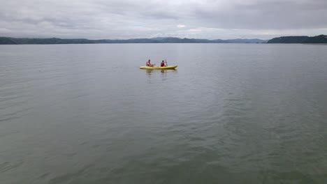 Aerial-of-two-people-doing-kayaking-in-calm-sea-on-an-overcast-day,-Nacascolo-beach-in-Papagayo-Peninsula,-Costa-Rica