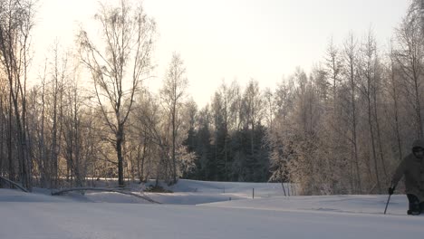 Hombre-Vestido-Con-Abrigo-De-Nieve-Caminando-En-Un-Campo-Rodeado-De-Bosque