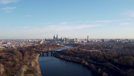 A-beautiful-aerial-drone-shot,-drone-flying-over-a-river-moving-towards-the-Philadelphia-skyscraper-skyline,-Pennsylvania
