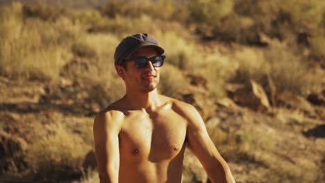 Close-up-front-view-of-a-young-shirtless-American-boy-in-sunglasses-firing-two-handguns-rapidly