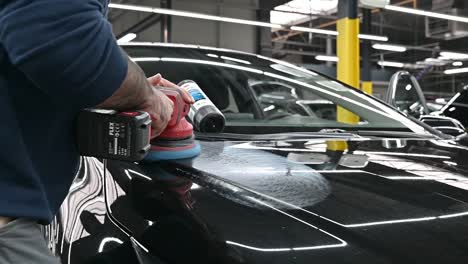 Garage-worker-polishing-black-hood-of-modern-vehicle,-close-up-motion-shot