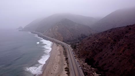 Aerial-drone-shot,-drone-descends-close-to-the-highway-in-Point-Mugu-State-Park,-Santa-Monica,-California