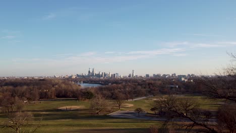 A-beautiful-aerial-drone-shot,-drone-landing-in-a-park-viewing-the-Philadelphia-skyscraper-skyline,-Pennsylvania