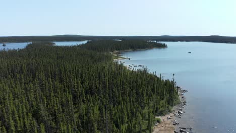 Drone-flying-over-the-shore-of-a-lake-on-a-summer-day