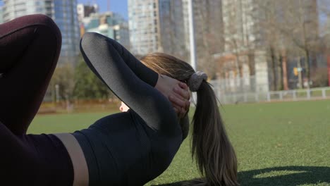 Athletic-young-woman-doing-knee-to-elbow-abdominal-exercise-in-park