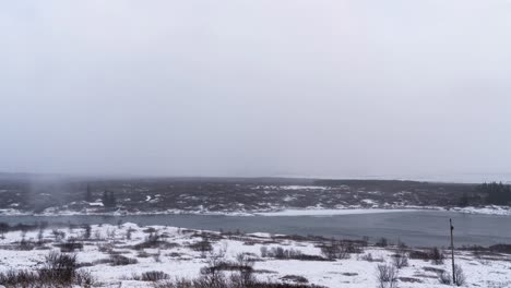 Tiro-De-Lapso-De-Tiempo-De-Día-De-Invierno-Ventoso-Y-Tormentoso-En-Islandia-Con-Olas-De-Río,-Tormenta-De-Nieve-Y-Paisaje-Cubierto-De-Nieve