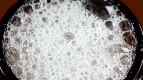 Macro-shot-of-beer-bubbles-bursting,-exploding-at-the-finish-of-a-plastic-bottle
