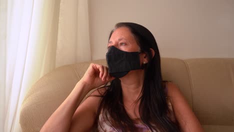 Depressive-Nachdenkliche-Dame-Mit-Gesichtsmaske-Sitzt-Während-Einer-Covid-pandemie-Zu-Hause-Am-Fenster