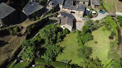Aerial-shot,-drone-flying-backward-from-a-little-town-on-the-valley-of-the-green-mountains-of-Asturias,-Spain