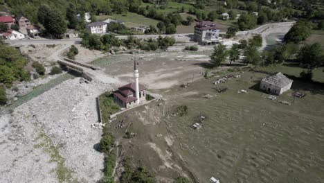 Spiral-shot-drone-video-over-an-orthodox-church-located-on-the-river-bank-in-valbona-valley,-albania,-Margegaj-county