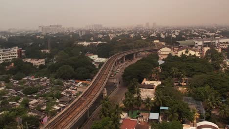 Metro-railway-going-through-the-middle-of-the-city-surrounded-by-trees,-buildings-and-roads