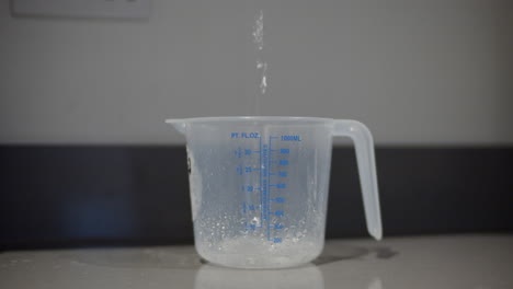 Clear-liquid-pouring-into-measuring-jug-for-school-science-experiment